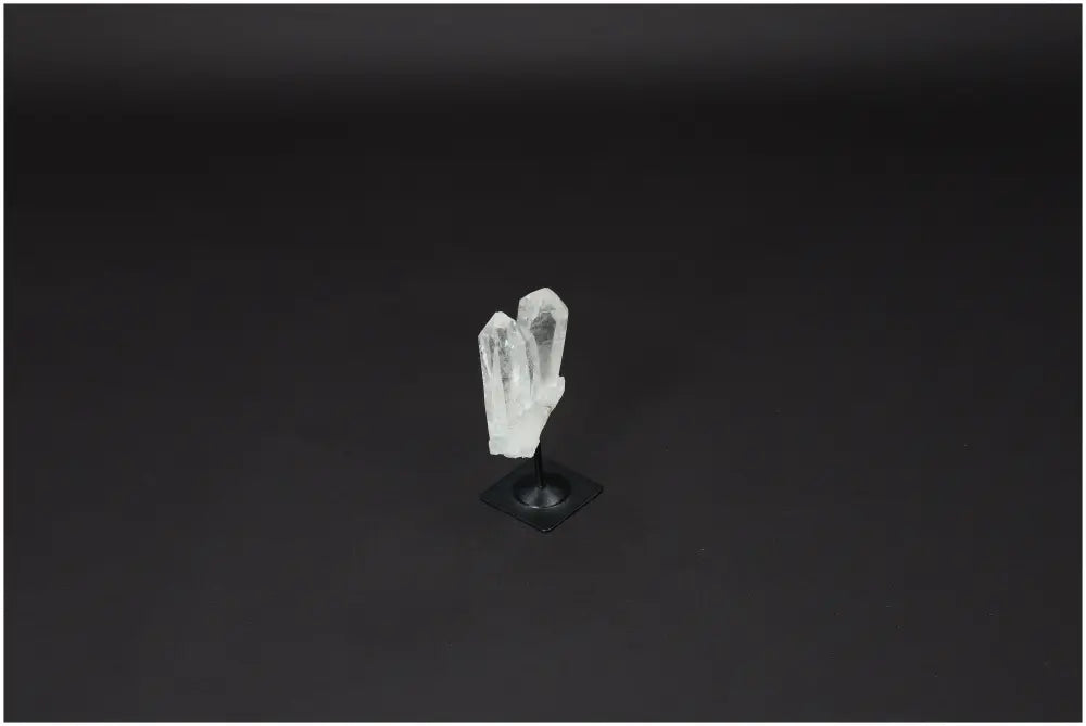 Lemurian Quartz Crystal on a metal stand, known for its purification properties, displayed against a dark backdrop.