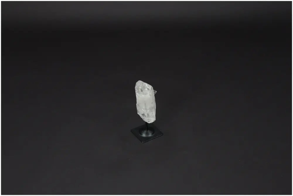Lemurian Quartz on a black metal stand against a dark background, crystal known for purification and harmonizing energy.