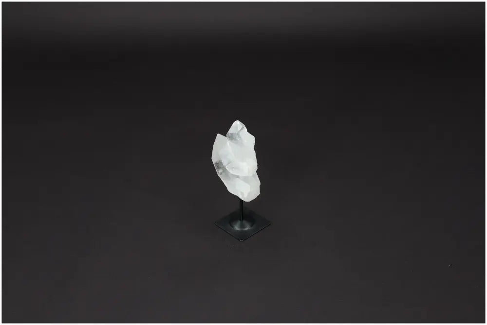 Lemurian Quartz crystal on metal stand against a dark background, known for purification and neutralizing negative vibrations.