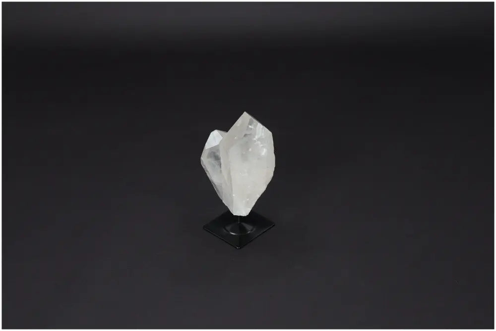 Lemurian Quartz on metal stand against dark background; Clear Quartz for purification, harmonizing mind and energy.