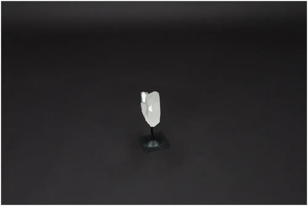 Lemurian Quartz on metal stand against dark background, showcasing its clear crystal structure and purifying energy attributes.