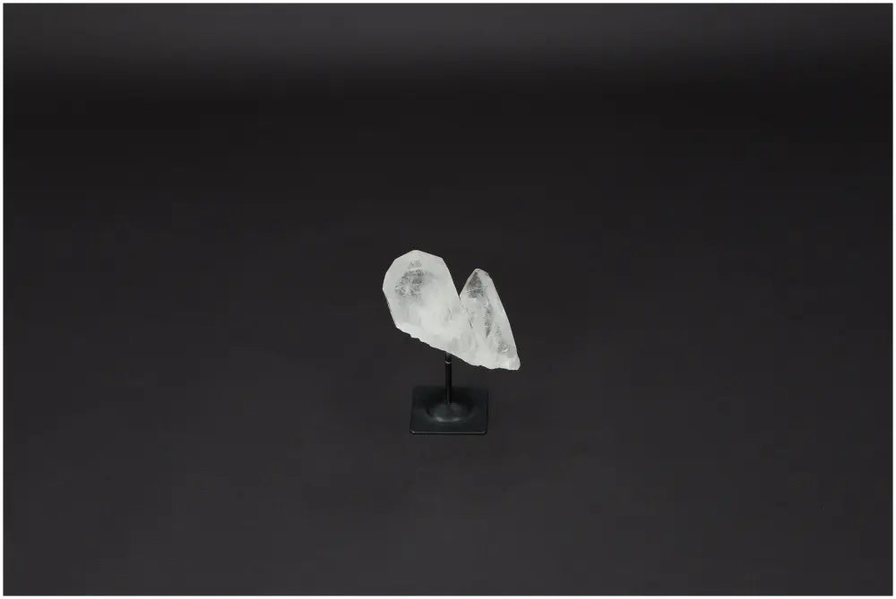 Lemurian Quartz on a metal stand, showcasing its natural clarity and purification properties against a dark background.