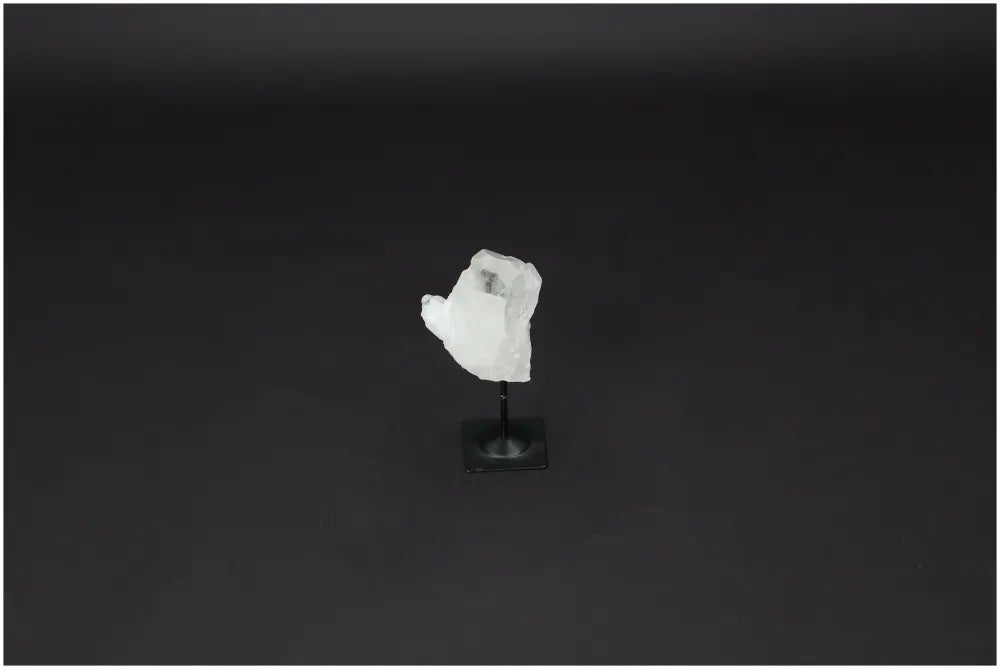 Lemurian Quartz on metal stand against dark background, known for powerful purification and harmonizing negative energy.