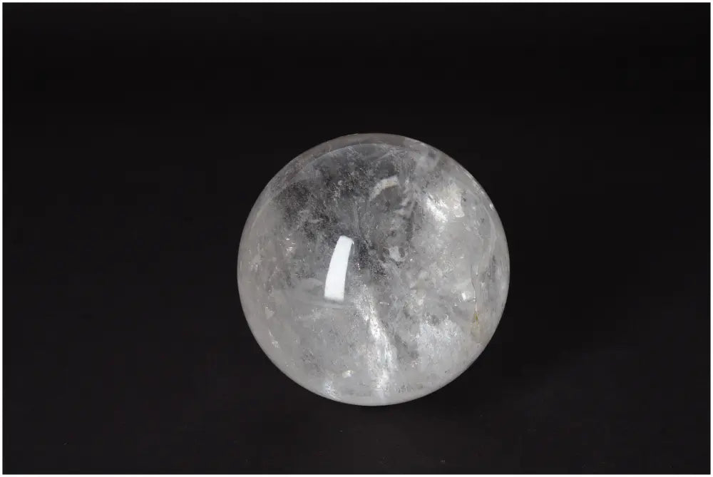 Lemurian Quartz Sphere on dark background, showcasing luminous clarity and subtle striations, promotes spiritual growth and intuition.