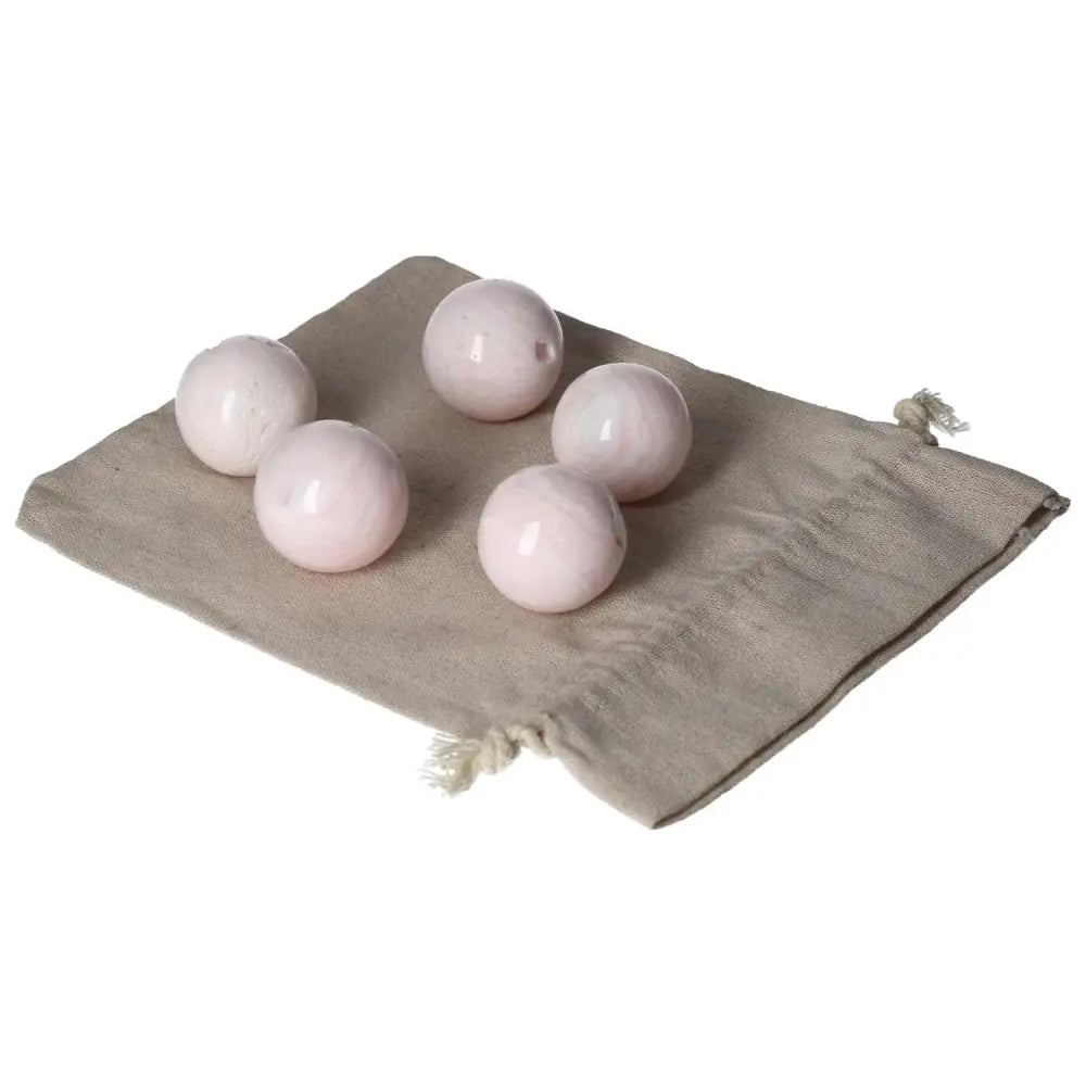 Set of five Manganocalcite spheres on a beige cloth, promoting healing and creativity benefits.