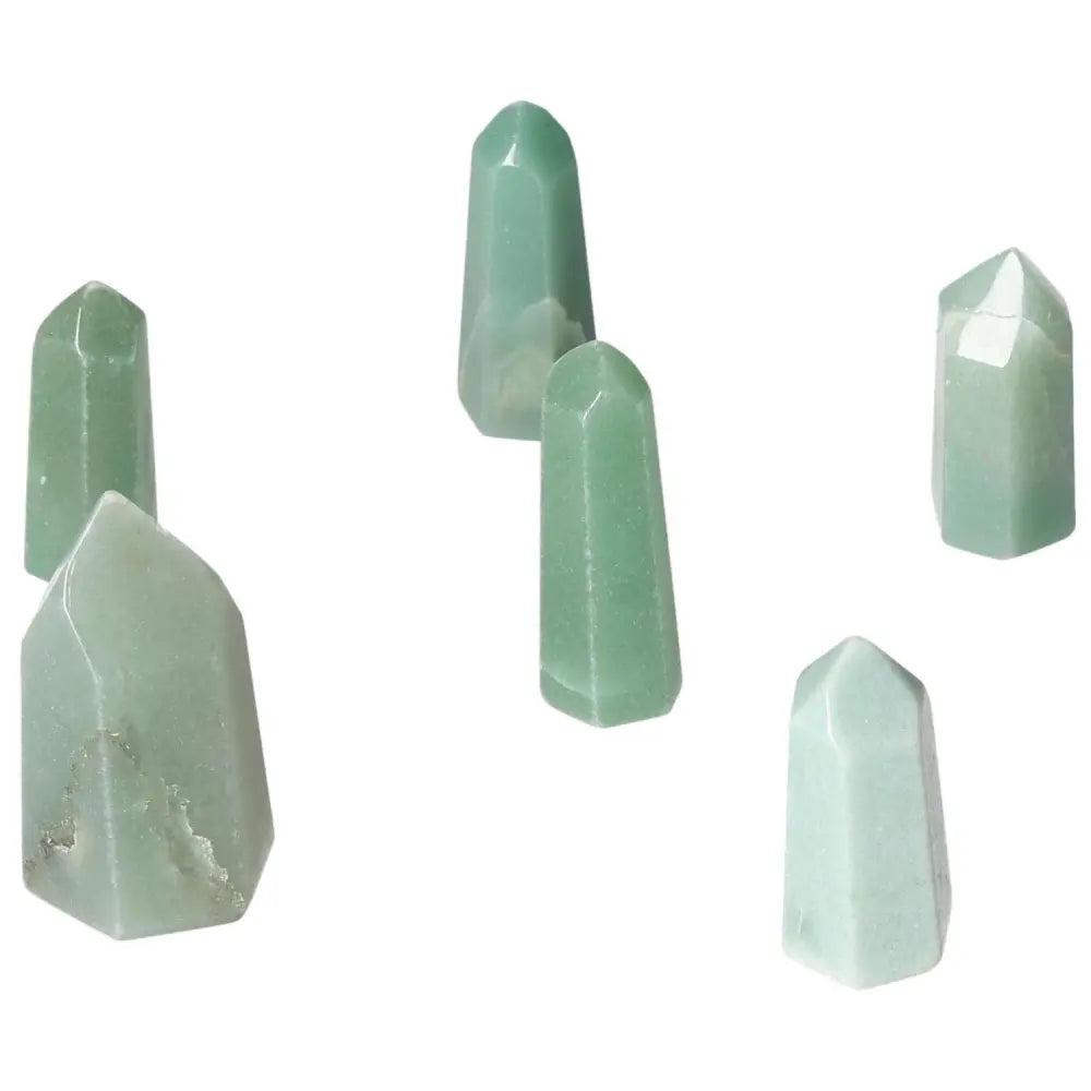 Mini point green quartz crystals arranged on a white background, showcasing their vibrant color and polished surfaces.