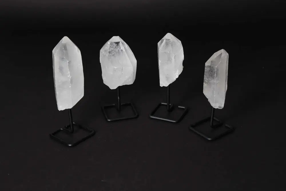 Four natural clear quartz points on modern stands, ideal for amplifying energy and enhancing clarity in meditation and energy work.