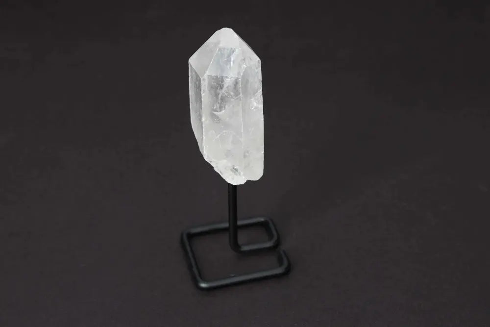 Natural Clear Quartz Point on a black stand for energy amplifying and clarity in meditation and manifestation practices.
