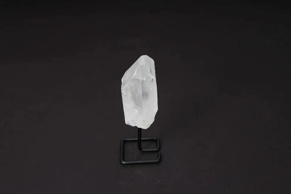 Natural Clear Quartz Point on Stand, ideal for meditation and energy work, amplifies energy and clarity, against a dark background.