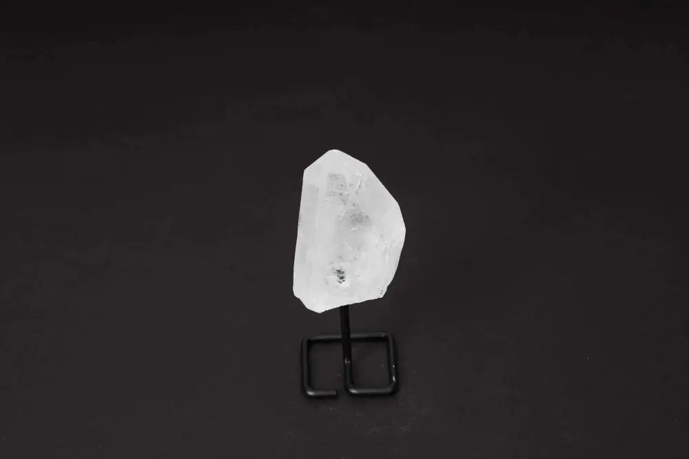 Natural Clear Quartz Point with stand on black background, ideal for amplifying energy and enhancing clarity in meditation and manifestation.