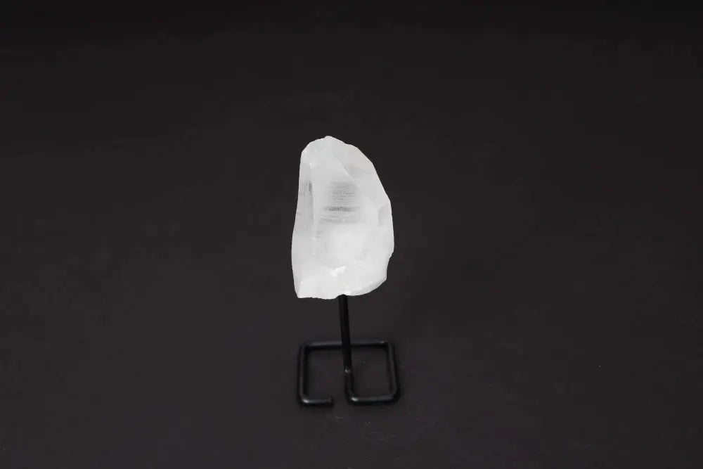 Clear Quartz Point on Stand, enhancing energy, clarity, and focus. Ideal for meditation, showcasing a refined design against a black backdrop.