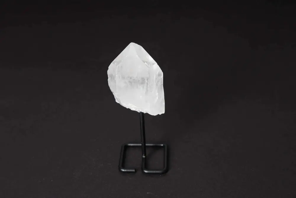 Natural clear quartz point on a stand for energy amplification and meditation, known as the Master Healer, enhancing clarity and focus.