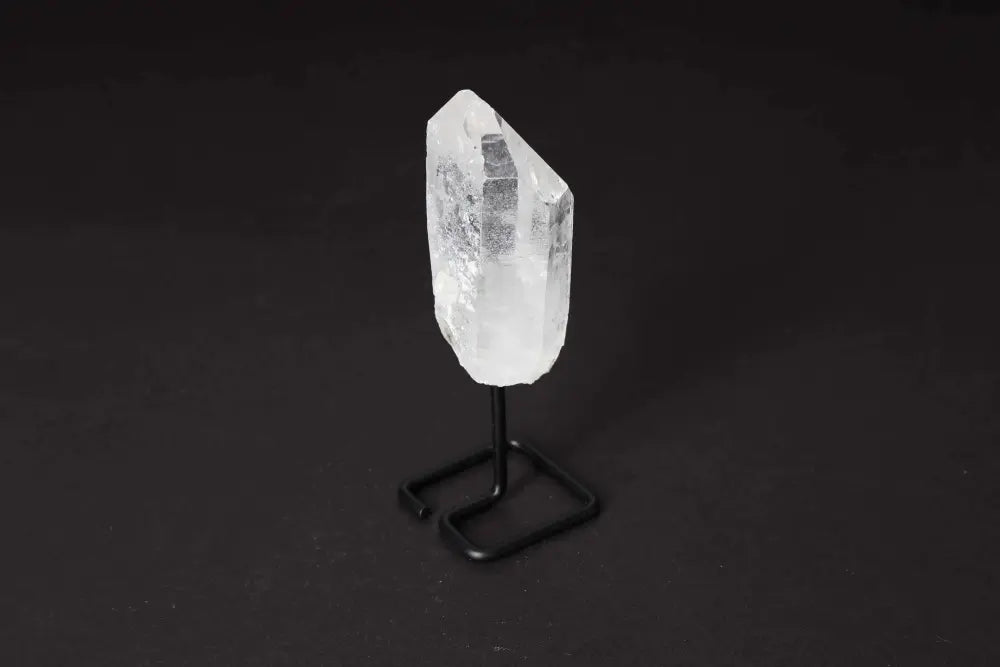 Clear Quartz Point with stand, amplifies energy and clarity, ideal for meditation and energy work on a black background.