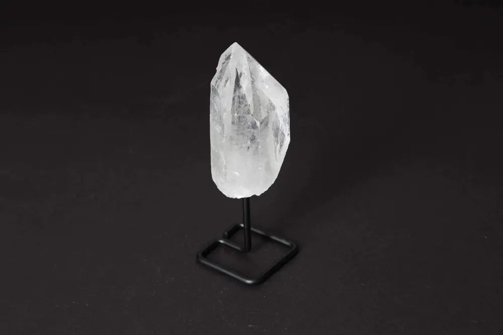 Natural Clear Quartz Point with Stand for energy amplification and meditation, displayed on a sleek black stand against a dark background.