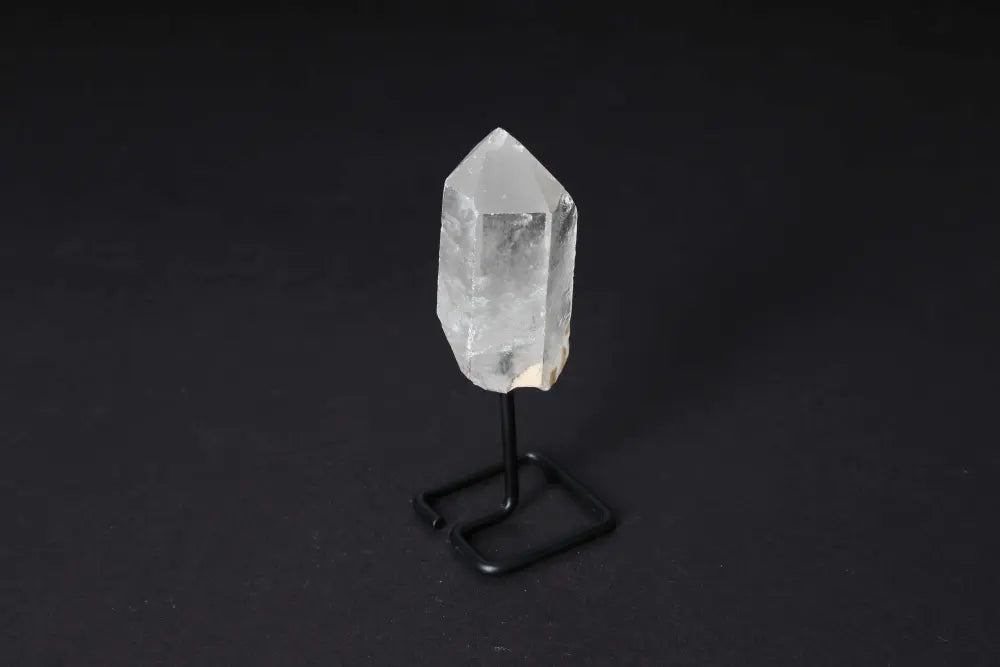 Natural clear quartz point on a black stand, enhancing energy and clarity, ideal for meditation, manifestation, and elegant decoration.