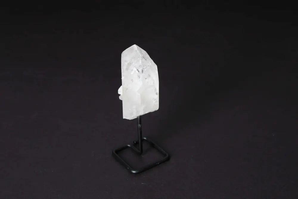 Natural Clear Quartz Point with stand, known for amplifying energy and clarity, against dark background.