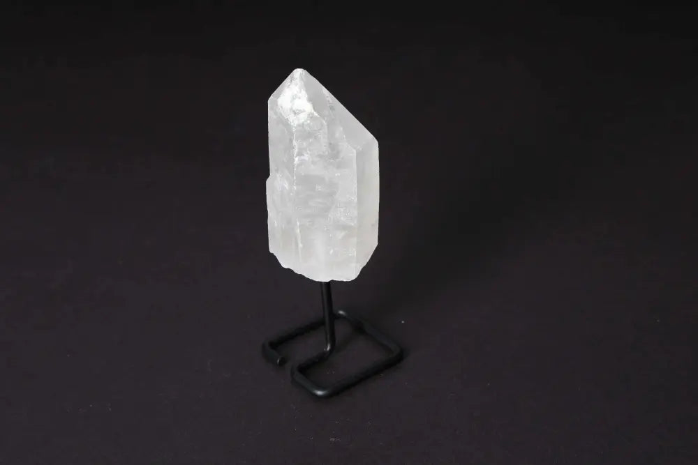 Natural Clear Quartz Point on modern stand, a powerful energy amplifier for meditation and clarity, displayed against dark background