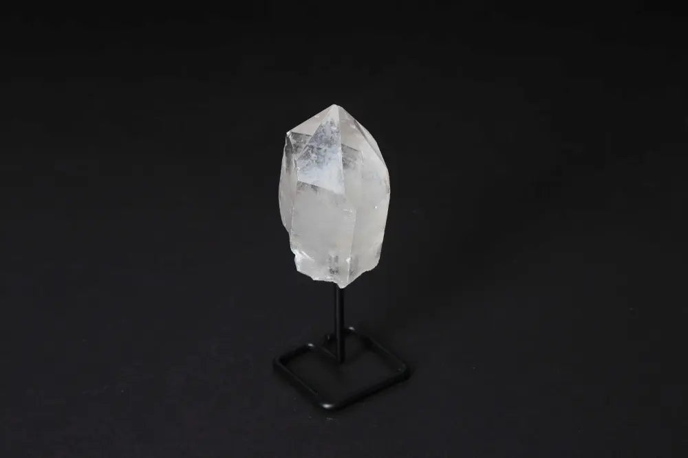 Clear Quartz Point on a stand against a black background, showcasing its crystal clarity and elegant presentation.