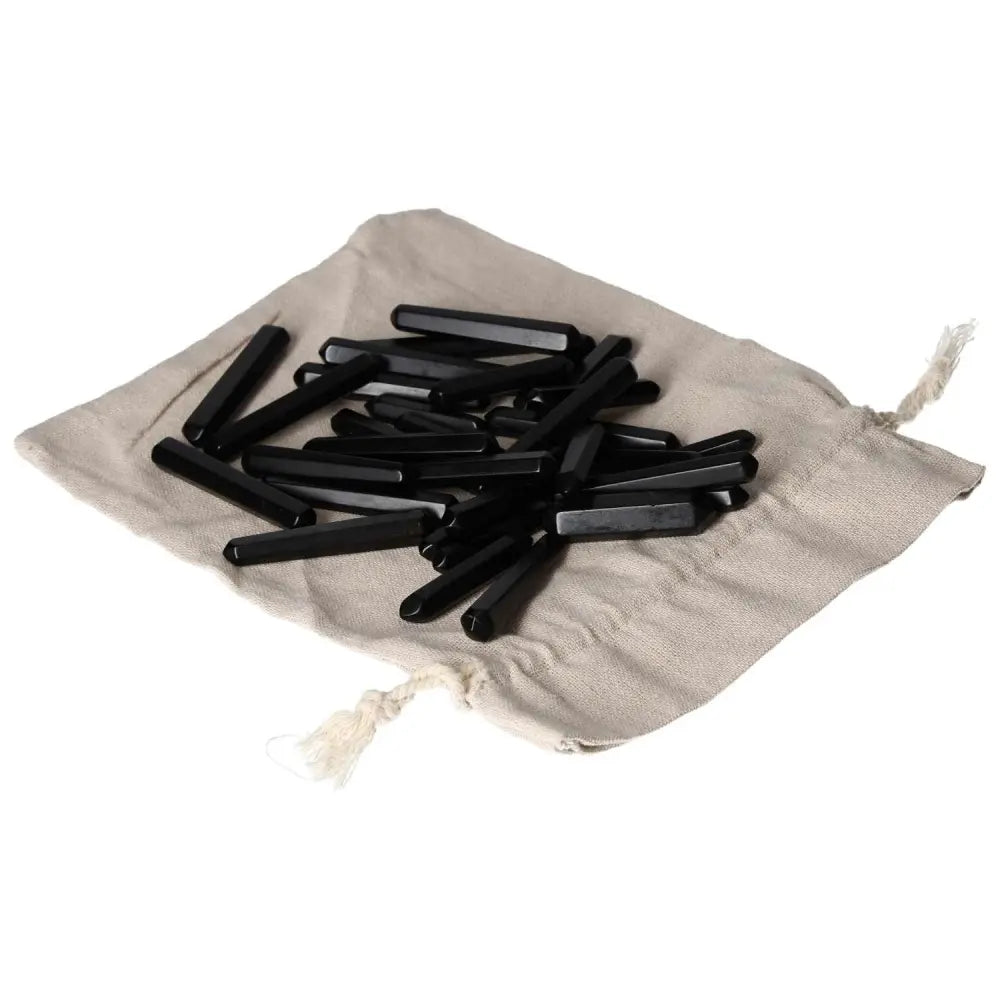 Pile of small obsidian sticks for protection on a linen cloth, absorbing negative energy and shielding against harmful influences.