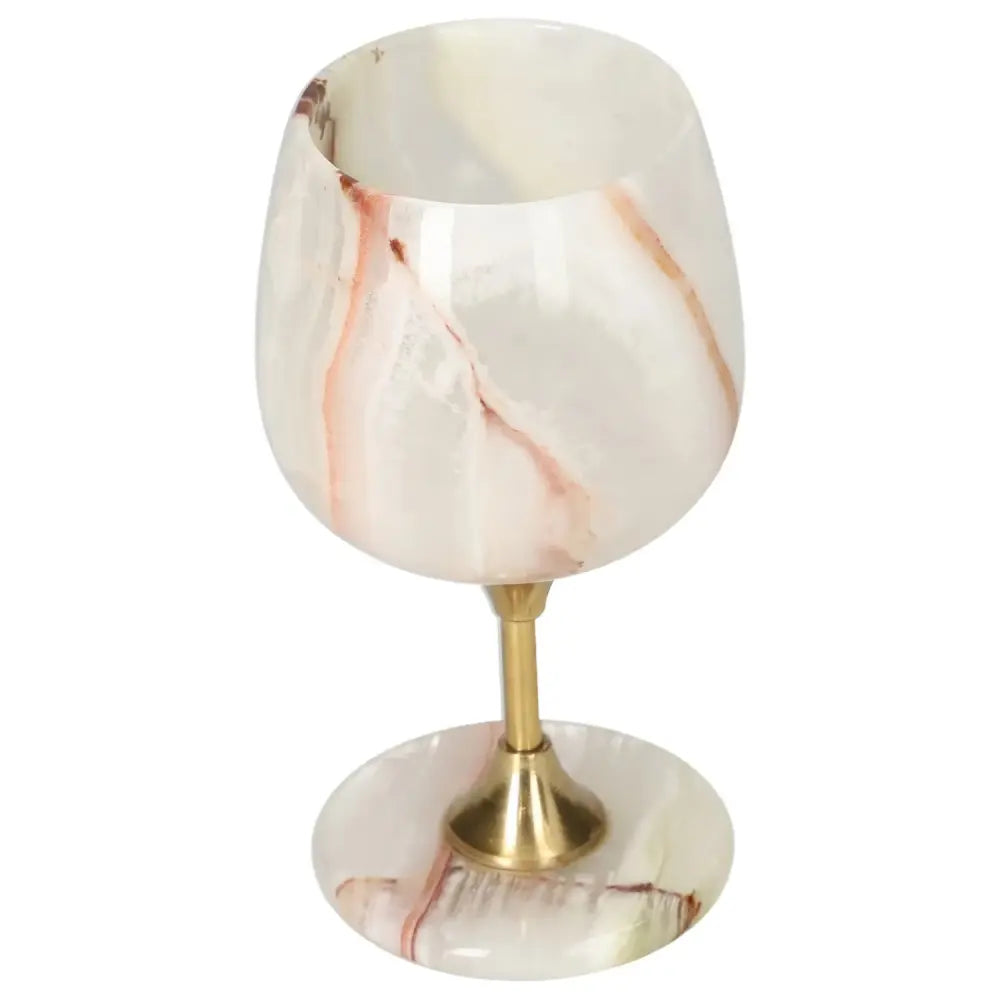 Exquisite onyx wine glass with unique veining, crafted in off-white stone with elegant brass stem, perfect for sophisticated occasions.