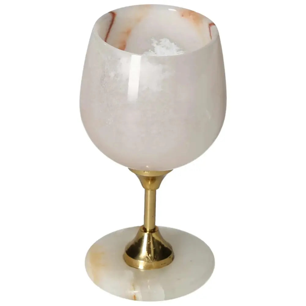 Elegant onyx wine glass with off-white hue and gold stem, showcasing unique veining and polished finish for sophisticated dining.