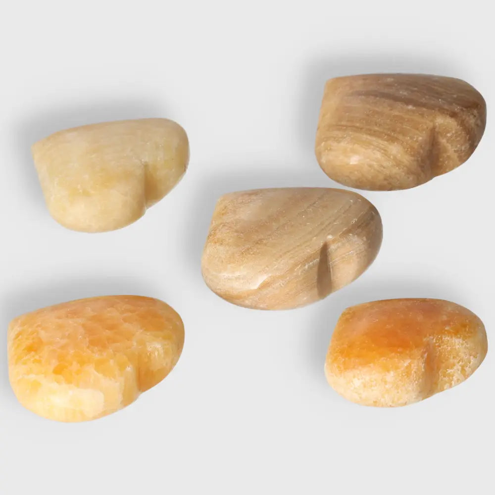 Orange Calcite Heart gemstones arranged on a white background, symbolizing love, joy, and renewal with vibrant, uplifting energy.