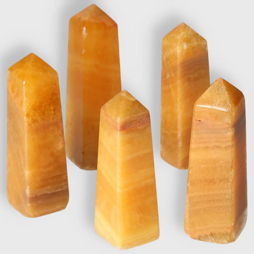 Five polished Orange Calcite Towers, ideal for meditation, emotional healing, and enhancing space ambiance with vibrant, glowing hues.