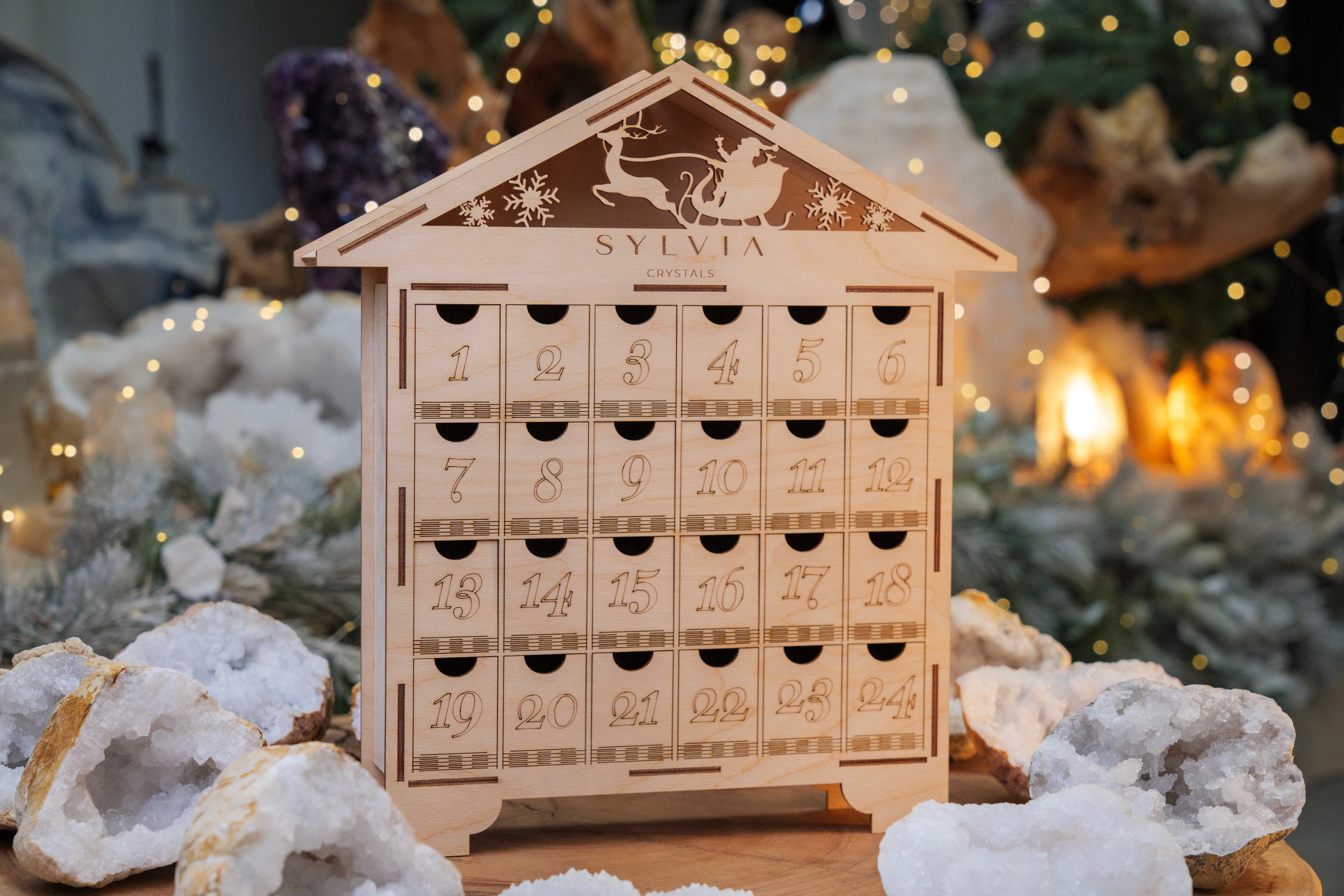 Wooden advent calendar with numbered doors surrounded by crystals and festive holiday decor.