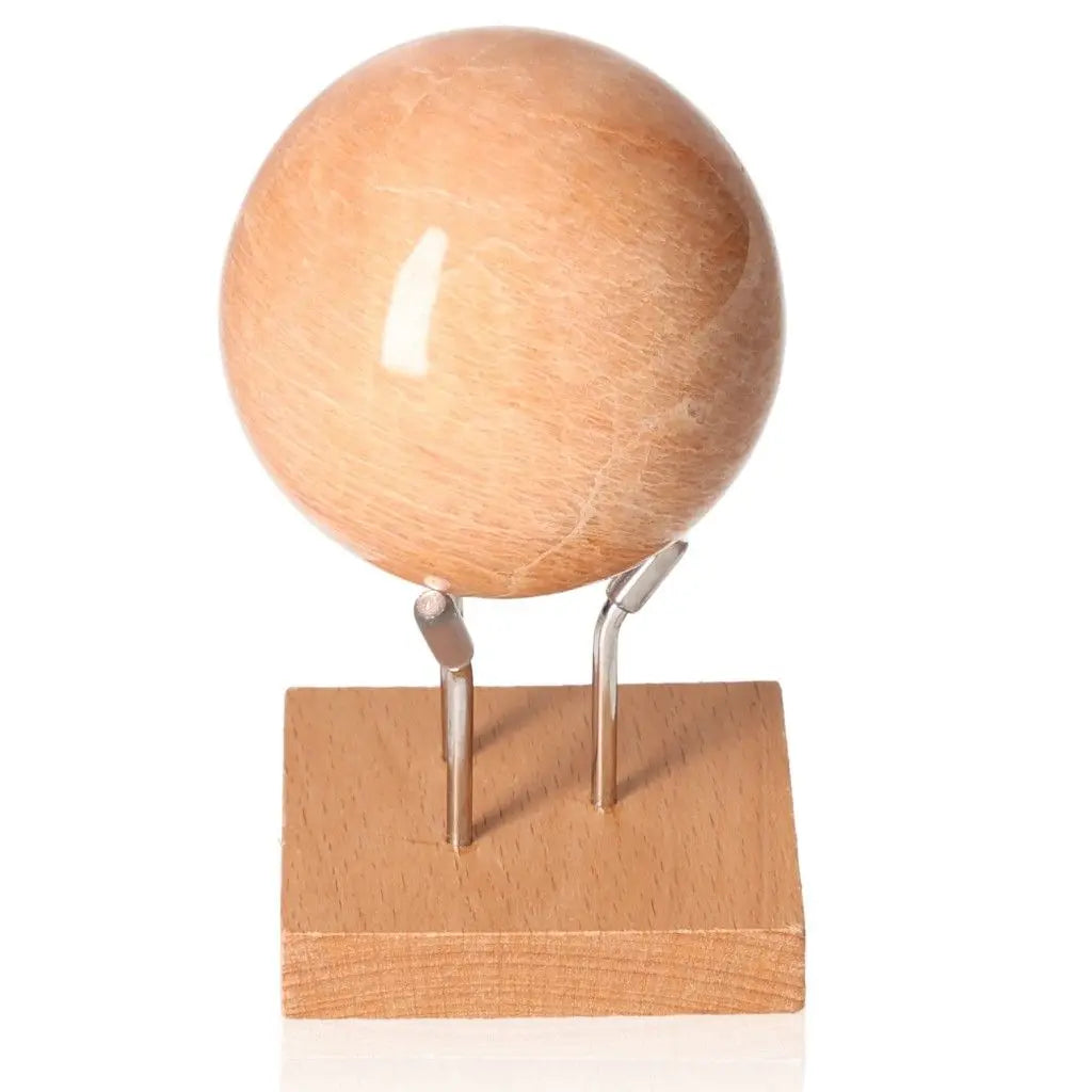 Peach Moonstone Sphere with soft peach hue on a wooden stand, symbolizing calmness and emotional healing.