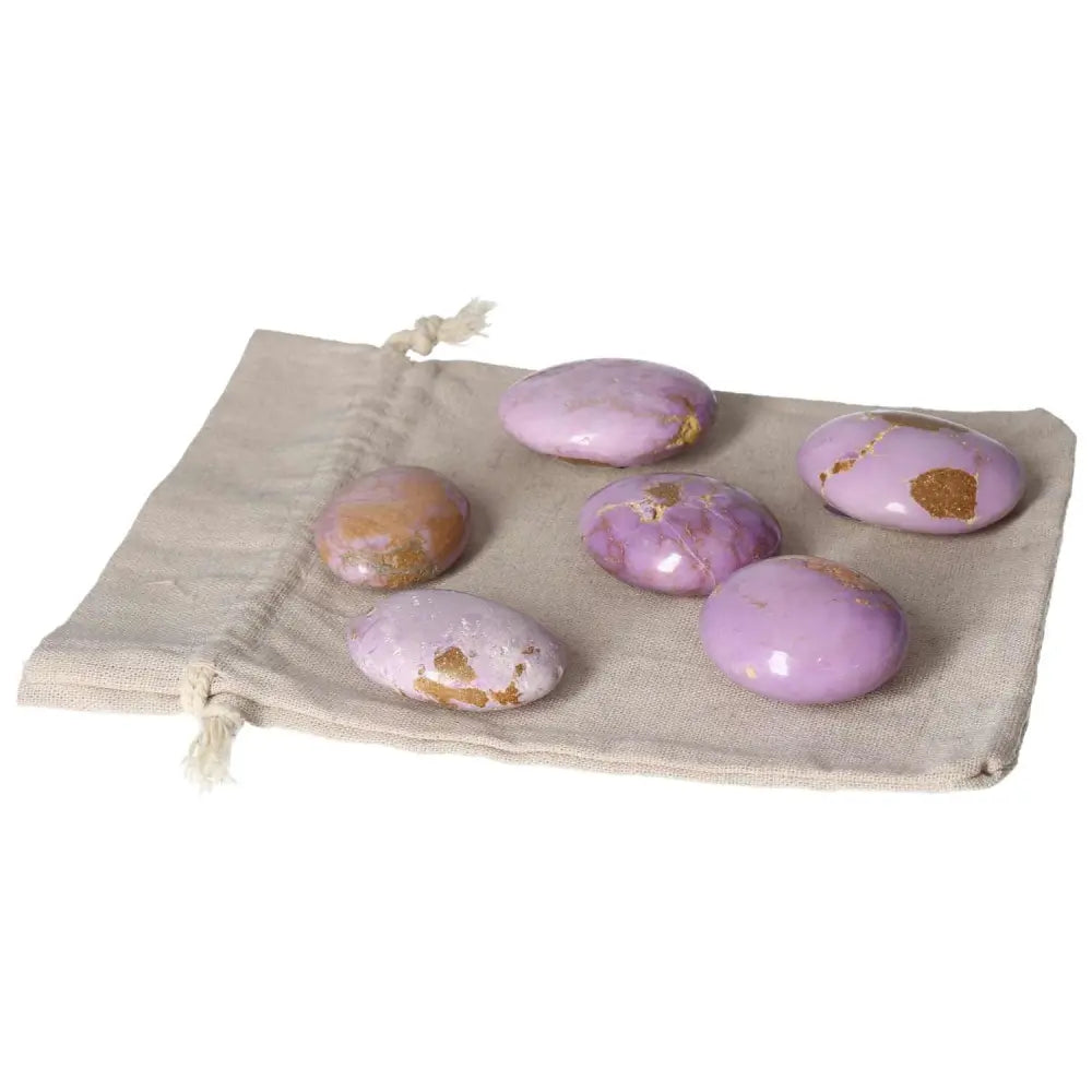 Set of polished Phosphosidente palmstones displayed on a beige cloth, featuring soft purple hues and natural markings.