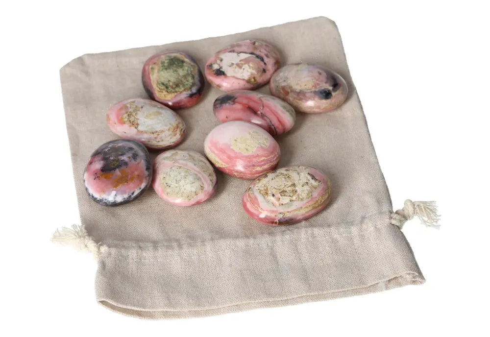 Pink Opal palmstones with opalescent sheen in pastel shades on a beige fabric bag promoting emotional healing and transformation.