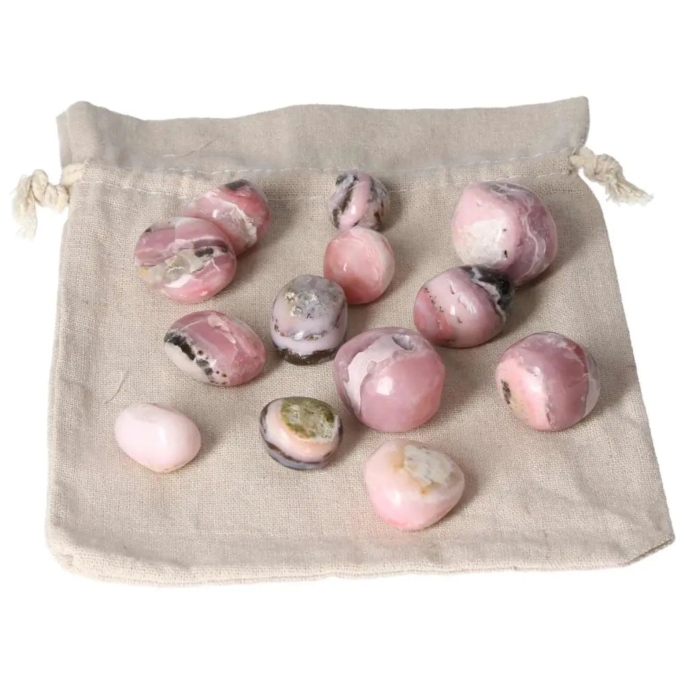Pink Opal tumbled stones with pastel pink hues displayed on a cloth bag, known for emotional healing and calming energy.