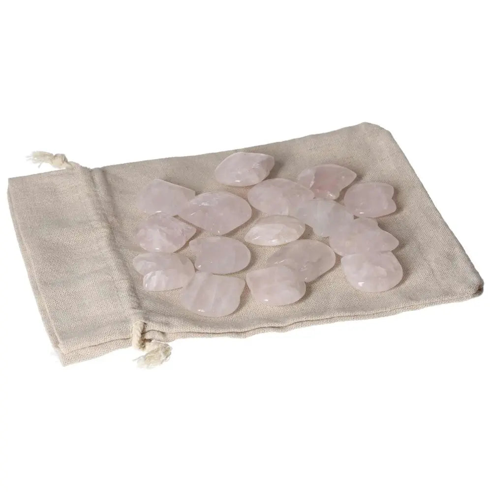 Assorted small pink quartz stones on a beige cloth bag for decorative or healing purposes.