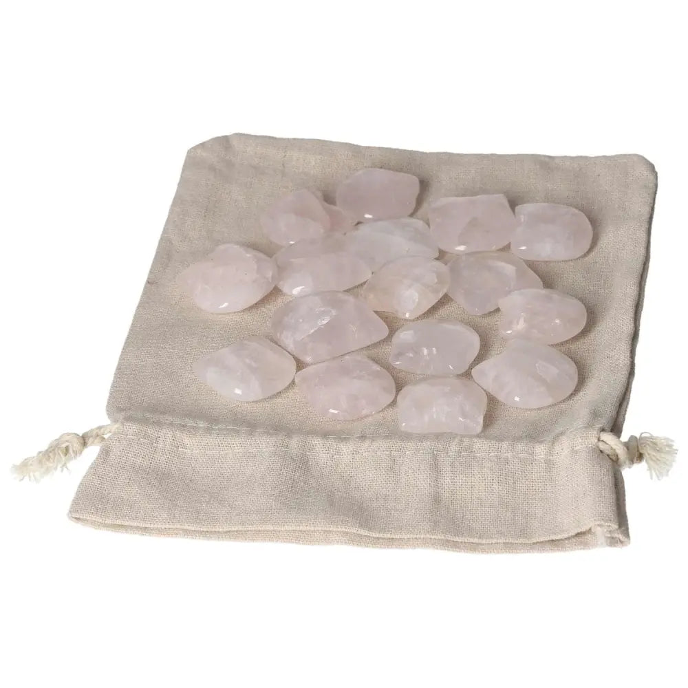 Collection of small polished pink quartz stones on a beige cloth pouch