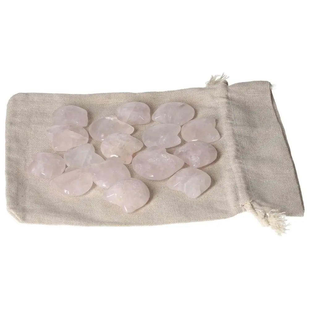 Smooth pink quartz stones on a beige cloth bag.