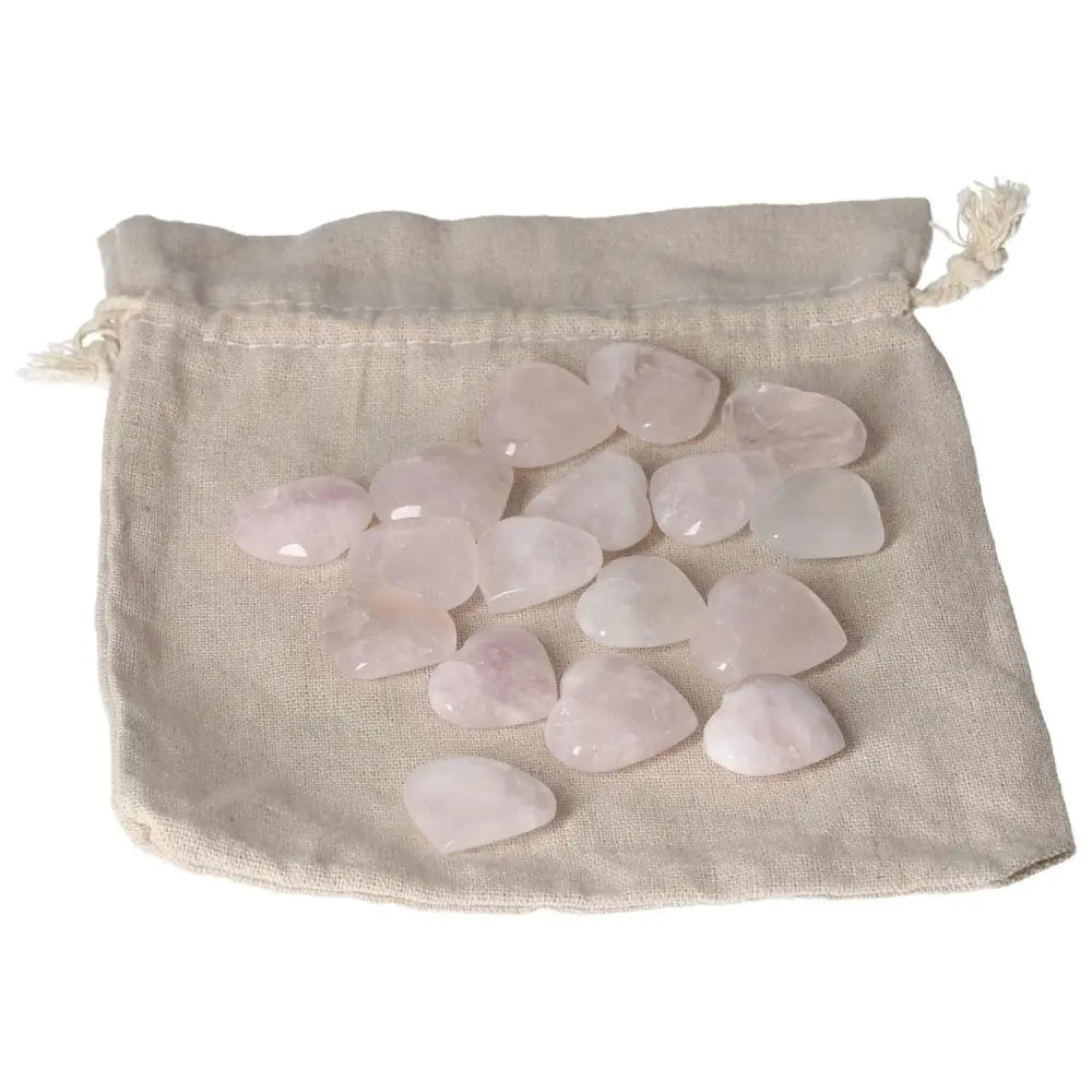 Collection of small pink quartz heart stones displayed on a linen pouch.