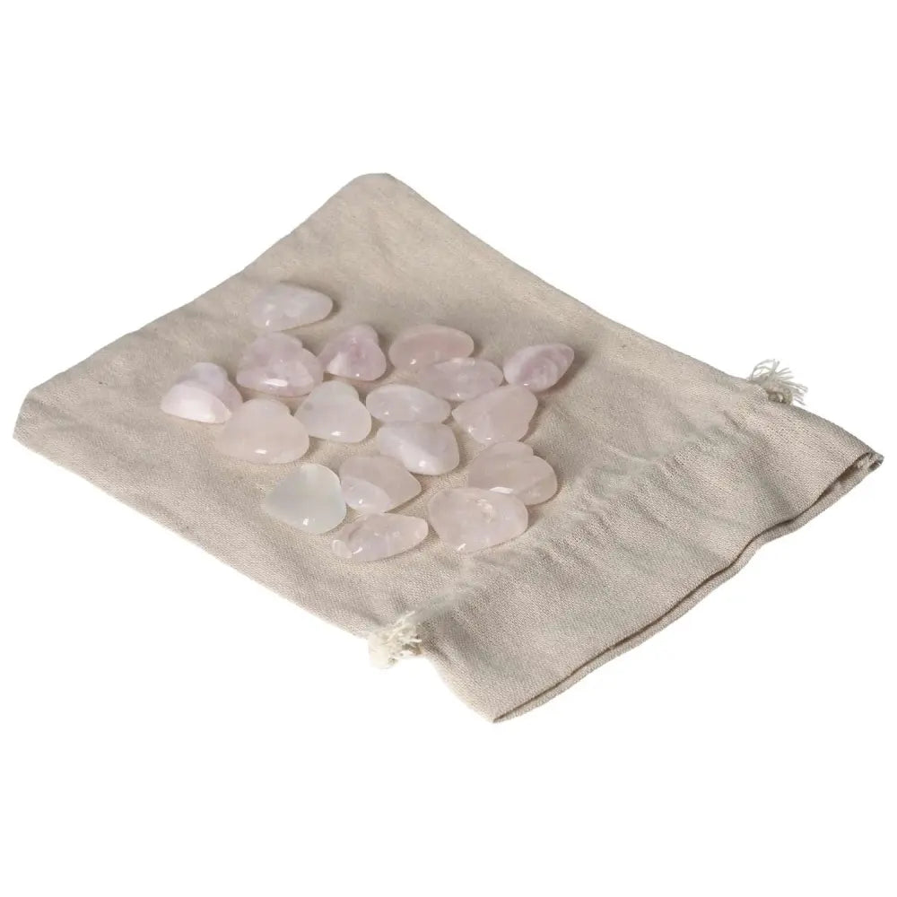Collection of small pink quartz heart-shaped stones on a beige cloth.