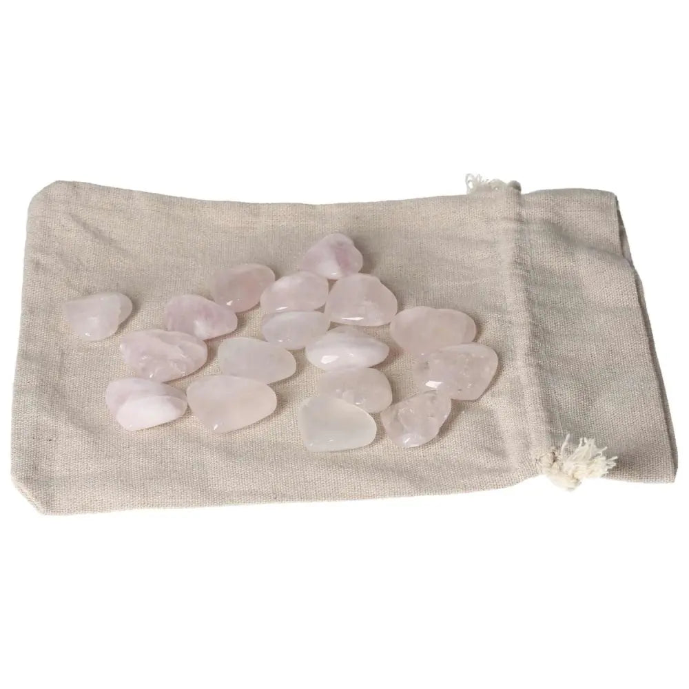 Pink quartz small heart stones spilling from a linen bag, highlighting their soft, pastel hues and smooth, polished surfaces.