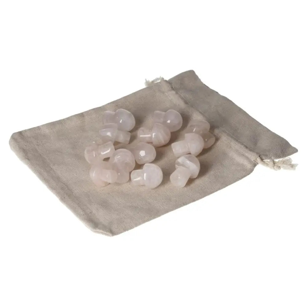 Collection of small pink quartz mushroom carvings on a beige fabric pouch, showcasing natural crystal aesthetics.
