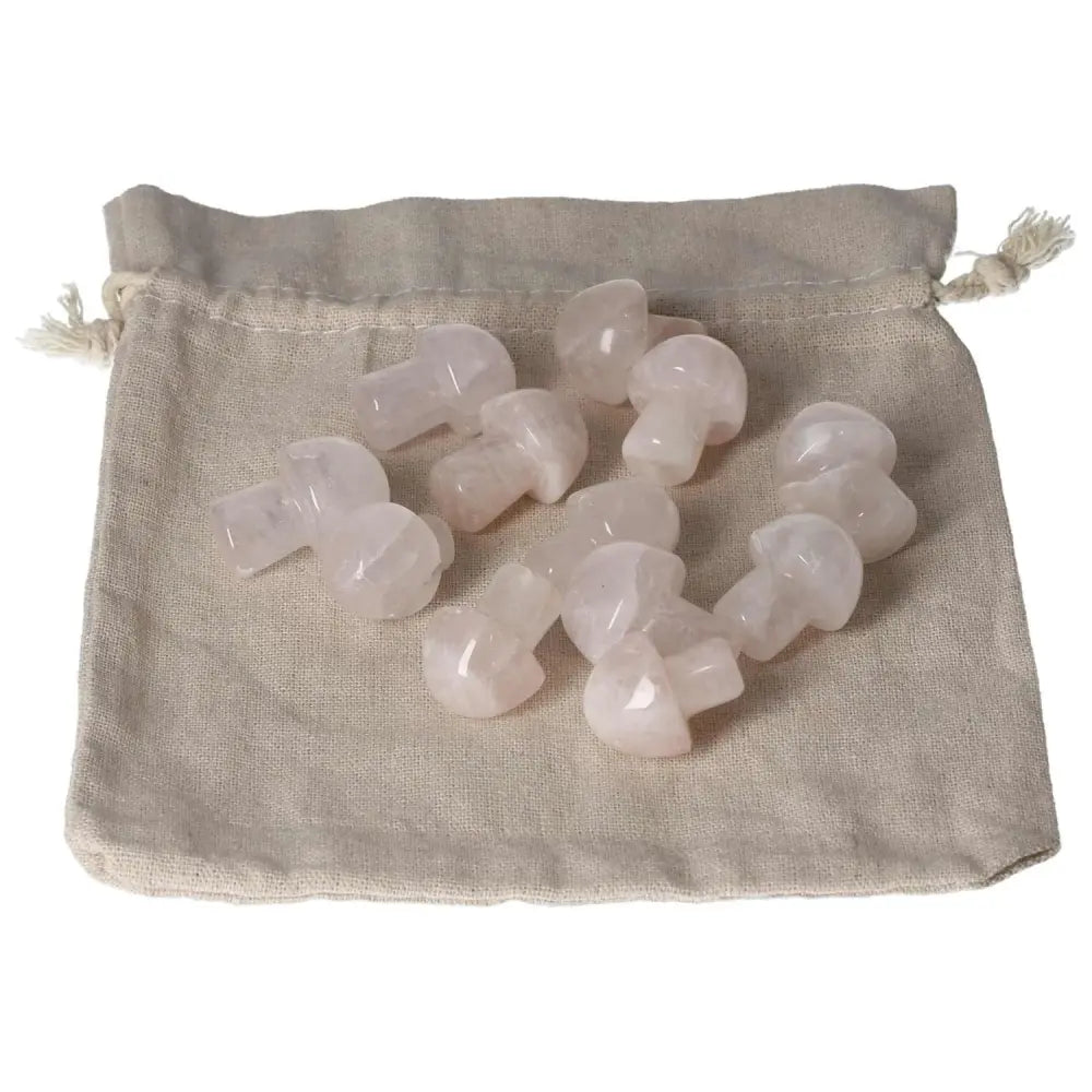 Collection of small pink quartz mushroom carvings placed on a beige fabric pouch, showcasing their delicate and polished design.