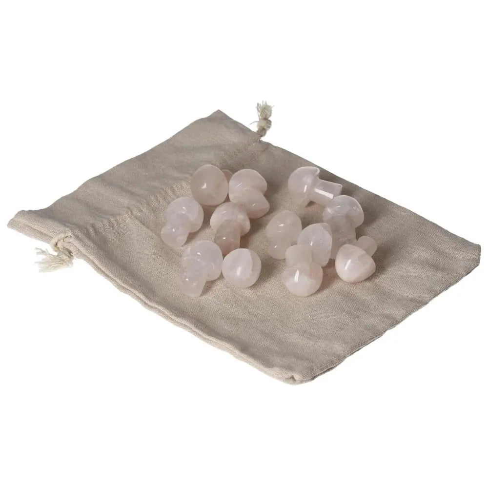 Pink quartz small mushrooms resting on a beige fabric pouch, highlighting their delicate shape and smooth texture.