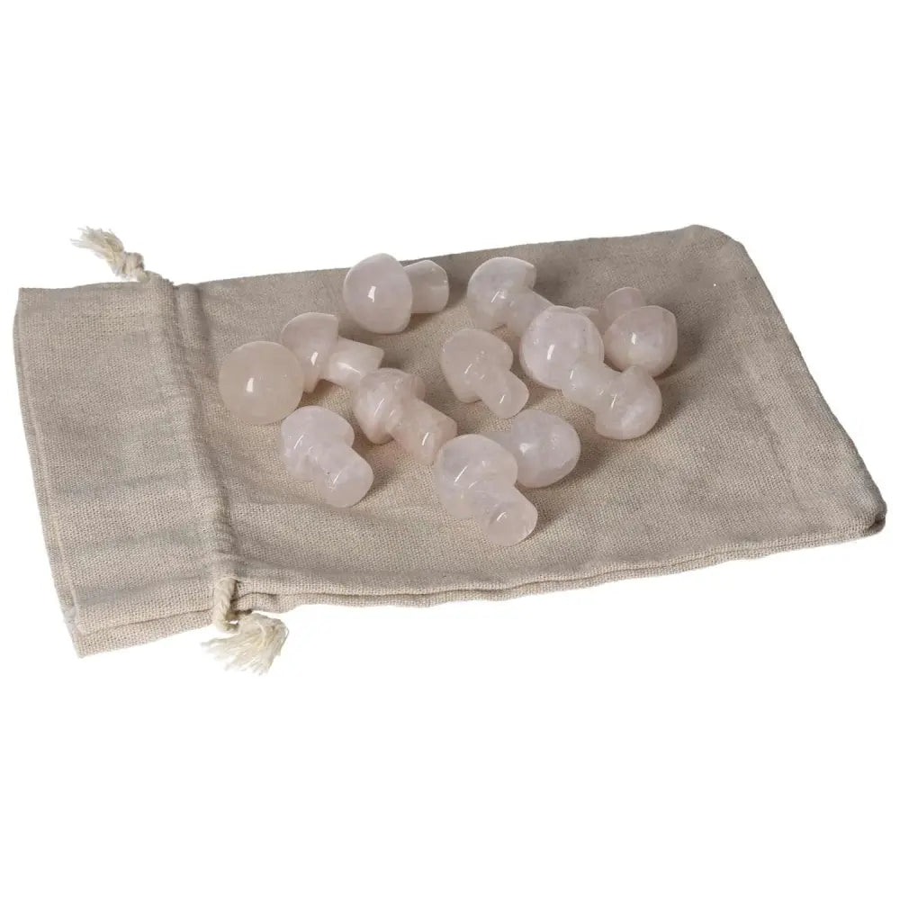 Small pink quartz mushroom figurines on a beige cloth pouch.