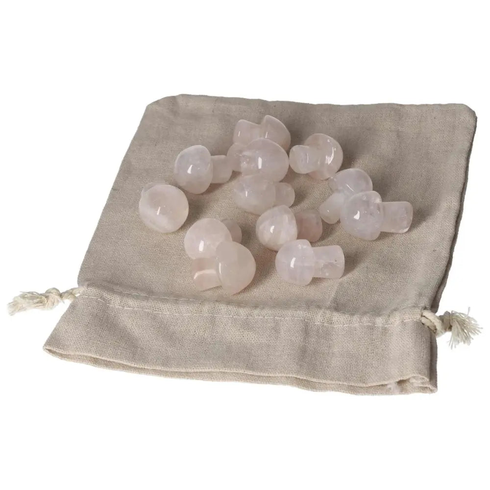 Small pink quartz mushroom stones on a beige cloth bag, decorative and healing crystals.