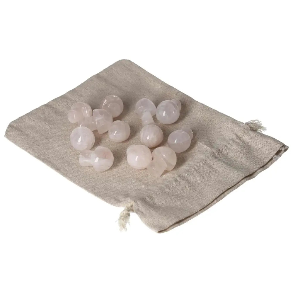Collection of small pink quartz mushroom stones on a beige drawstring bag.