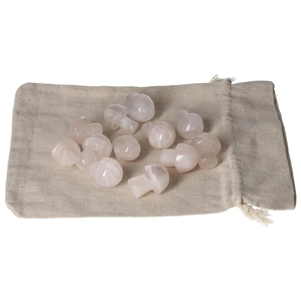 Collection of small pink quartz mushroom stones on a beige cloth bag, perfect for crystal healing and decor.