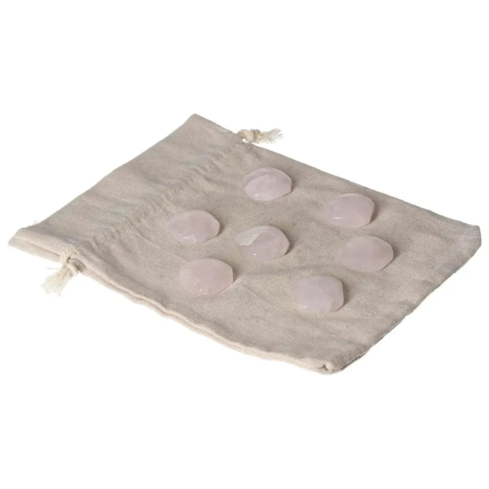 Set of small pink quartz palmstones on a cloth, ideal for emotional healing and heart chakra support.