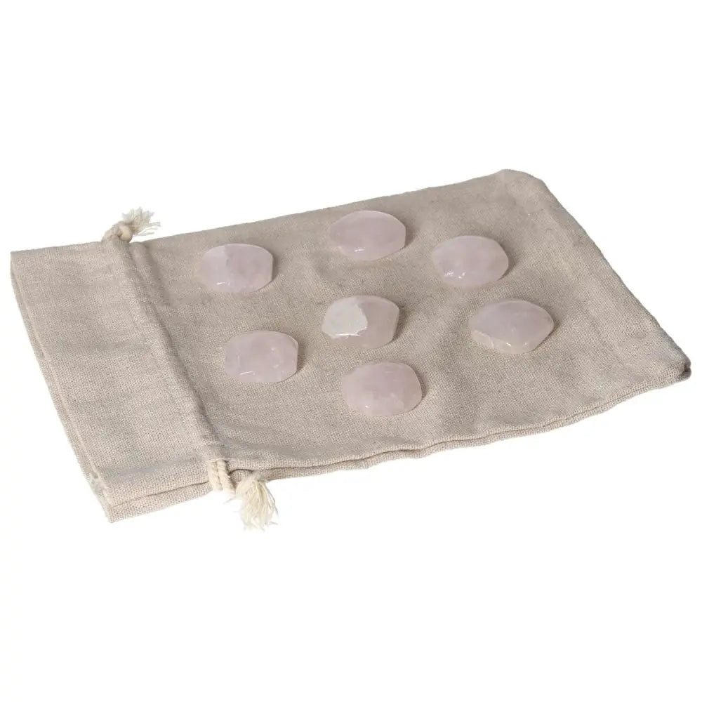 Small pink quartz palmstones on a fabric bag, ideal for heart chakra healing and emotional balance.
