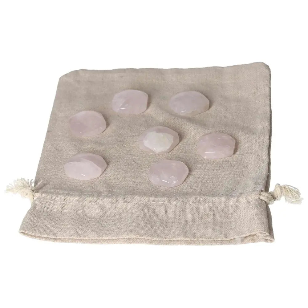 Collection of small pink quartz palmstones on beige pouch, ideal for self-care, emotional healing, and heart chakra support.