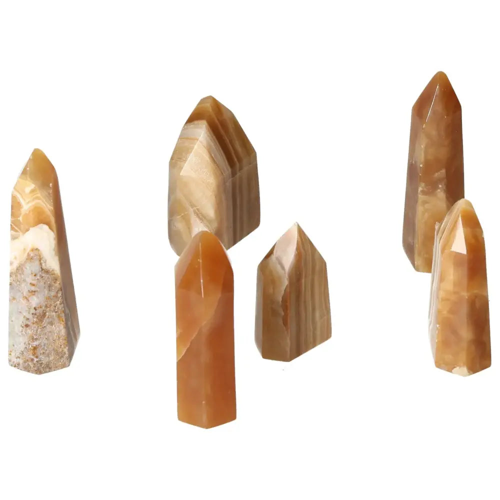 Six polished honey calcite points from Sylvia Crystals, showcasing natural warm tones that symbolize prosperity and positive transformation.