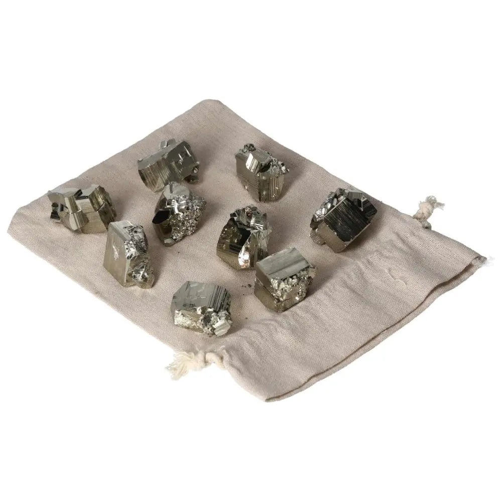 Collection of polished pyrite cubes on a beige cloth, showcasing their radiant golden luster and grounding energy properties.
